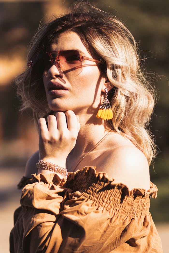 Stylish woman in sunglasses posing outdoors with elegant fashion accessories in summer.